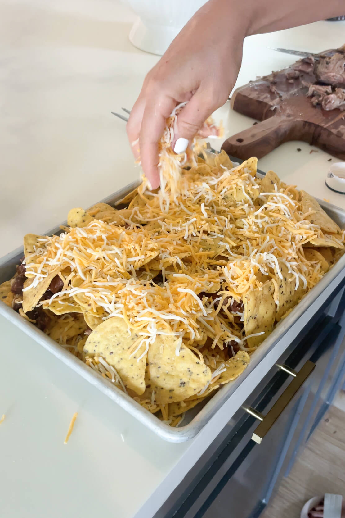 Adding more cheese to smoked brisket nachos.